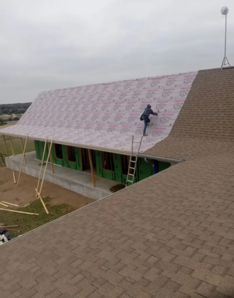 Worker preparing underlayment for a metal roof installation in Cerritos